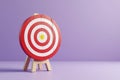 Red and white target board on wooden easel for archery with copy space on a vibrant lavender background Royalty Free Stock Photo