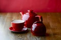 Red and white tea set with on dark wooden table with hot pink background. Royalty Free Stock Photo