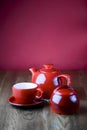 Red and white tea set with on dark wooden table with hot pink background. Royalty Free Stock Photo