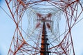 Red white telecommunication tower against blue sky - bottom view