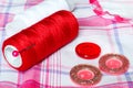 Red and white thread and buttons on a checkered cloth. Sewing accessories Royalty Free Stock Photo
