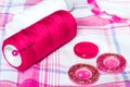 Red and white thread and buttons on a checkered cloth. Sewing accessories Royalty Free Stock Photo