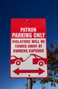 A red and white traffic sign, Patron parking only, violators will be towed away at owners expense.