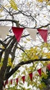 Red and white triangular bunting hanging against a background of bright yellow autumn foliage and sky Royalty Free Stock Photo