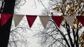 Red and white triangular bunting hanging against a background of bright yellow autumn foliage and sky Royalty Free Stock Photo