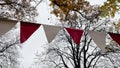 Red and white triangular bunting hanging against a background of bright yellow autumn foliage and sky Royalty Free Stock Photo