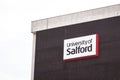 University of salford logo and sign on a bland and boring brickwall