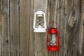 Red and white vintage handle gas lanterns on rustic wooden wall.