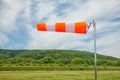 Red and white wind sock on blue sky, mounting and clouds background Royalty Free Stock Photo