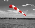 Red and white windsock wind sock  on the aerodrome, monochrome black and white field, sky and clouds background Royalty Free Stock Photo