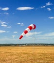 Red and white windsock wind sock on blue sky on the aerodrome, yellow field and clouds background in autumn Royalty Free Stock Photo
