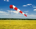 Red and white windsock wind sock on blue sky on the aerodrome, yellow field and clouds background Royalty Free Stock Photo