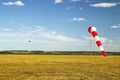 Red and white windsock wind sock on blue sky, yellow field and clouds background Royalty Free Stock Photo