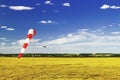 Red and white windsock wind sock on blue sky, yellow field and clouds background, silhouette of vintage airplane in the sky Royalty Free Stock Photo