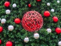 A red wicker ball entwined with a garland hangs among the spruce branches with small red and silver balls around