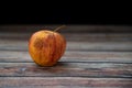 Red wilted rotten apple on a table. Bacteria infected rotten fruit