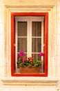 Red window with geraniums colorful flowers in clay pot