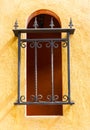 Red window with metal bar on yellow wall Royalty Free Stock Photo
