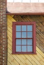 Red window on yellow diagonal wood with red brick