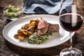 Red wine as a typical baverage to a red meat steak with roasted potatoes, spinach dip and fresh salad served on a white porcelain Royalty Free Stock Photo