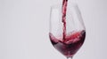 Red wine being poured into an empty transparent glass on a white background, close-up photo Royalty Free Stock Photo