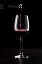 Red wine being poured into a glass and splashing over the side. Low key black background Royalty Free Stock Photo