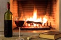 Red wine and a book on burning fireplace background