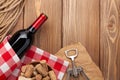 Red wine bottle, corks and corkscrew over wooden table background