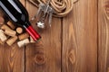 Red wine bottle, corks and corkscrew over wooden table background Royalty Free Stock Photo