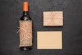 Red wine bottle, gift box wrapped in kraft paper, blank card for your message on black background. Zero waste. Top view Royalty Free Stock Photo