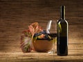 Red wine bottle, glass, grapes, wicker background Royalty Free Stock Photo