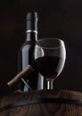 Red wine bottle with glass and vintage corkscrew on top of wooden barrel on black Royalty Free Stock Photo