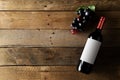 Red wine bottle with grapes on brown rustic wooden table flat lay from above Royalty Free Stock Photo