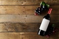 Red wine bottle with grapes on brown rustic wooden table flat lay from above Royalty Free Stock Photo