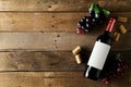 Red wine bottle with grapes and corks on brown rustic wooden table flat lay from above Royalty Free Stock Photo