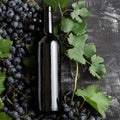 Red wine bottle grapes, grape bunches with leaves and vine on dark rustic concrete background. Flat lay wine composition on black Royalty Free Stock Photo