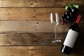 Red wine bottle with grapes and wine glass on brown rustic wooden table flat lay from above Royalty Free Stock Photo