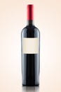Red wine bottle with blank text label isolated on warm gradient background