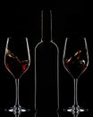 Red wine bottle and splashing wine in glasses on dark background Royalty Free Stock Photo