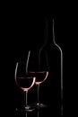 Red wine bottle and two wine glasses on black background on black background Royalty Free Stock Photo