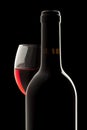 Red wine bottle and wine glass in a black backgrou