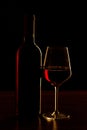 Red wine bottles and glass silhouette on wooden table and black background Royalty Free Stock Photo