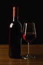 Red wine bottles and glass silhouette on wooden table and black background Royalty Free Stock Photo