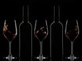 Red wine bottles and splashing red wine in glasses on dark background Royalty Free Stock Photo