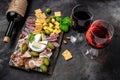 Red wine with charcuterie assortment Antipasto board with sliced meat, ham, salami, cheese, olives and wine on a dark background. Royalty Free Stock Photo