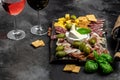 Red wine with charcuterie assortment Antipasto board with sliced meat, ham, salami, cheese, olives and wine on a dark background. Royalty Free Stock Photo