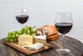 Red wine, cheese, grapes and bread on wood platter Royalty Free Stock Photo