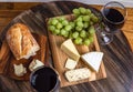 Overhead shot of wine, cheese, grapes and bread on wood platter Royalty Free Stock Photo