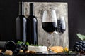 Red wine in classic glass with wine bottles composition. Elegant Wine bar menu with snacks cheese on dark moody Royalty Free Stock Photo