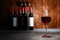 Red wine in clear glass, many blurred wine bottle backgrounds Place it on a cement floor with a wooden board wall. The cellar Royalty Free Stock Photo